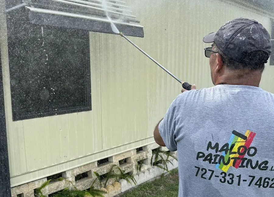 Crew member pressure washing a storefront wall and window awning