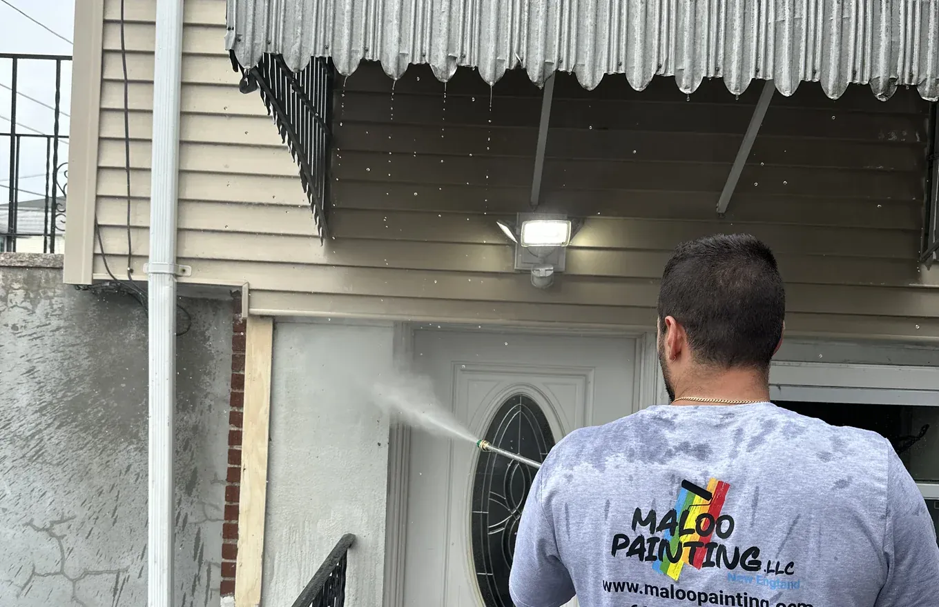 Crew member rinsing an entryway and siding clean